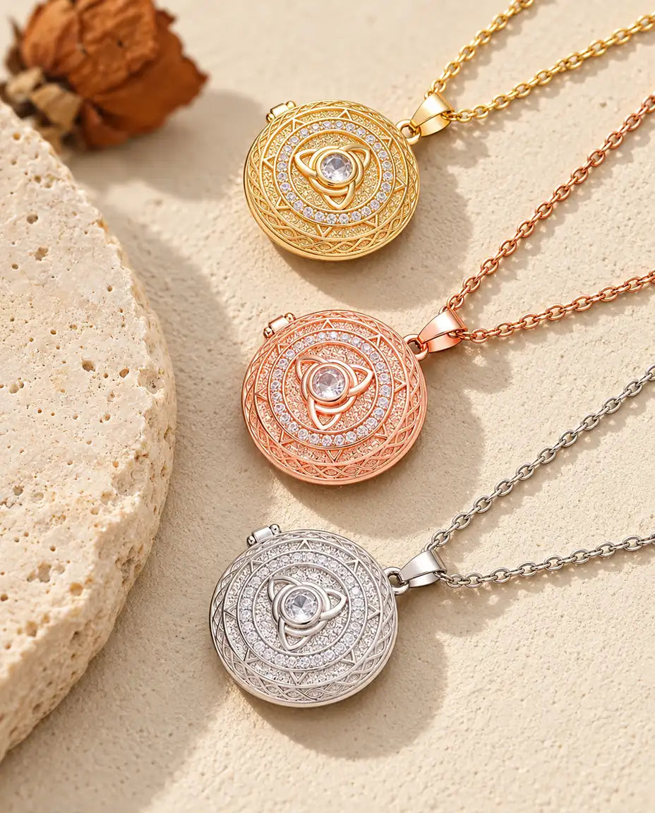 Gold tone, rose gold tone and silver tone trinity knot lockets stacked beside a travertine slab