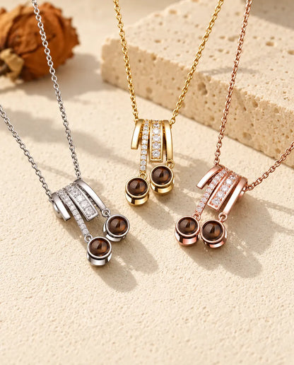 Two photo projection slide necklaces in silver tone, gold tone and rose gold tone hanging side by side
