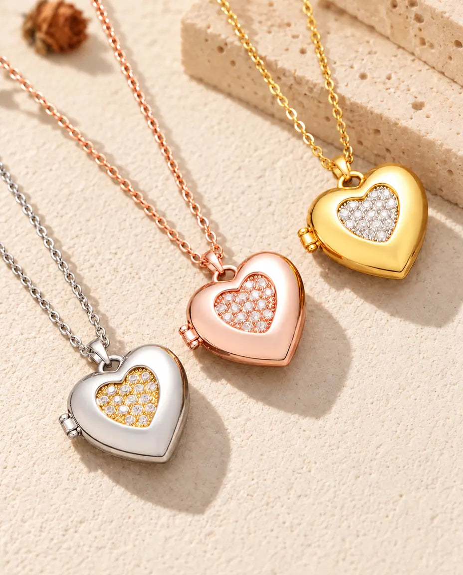 Two-tone pave heart photo lockets in silver tone, rose gold tone and gold tone laid diagonally on cream plaster