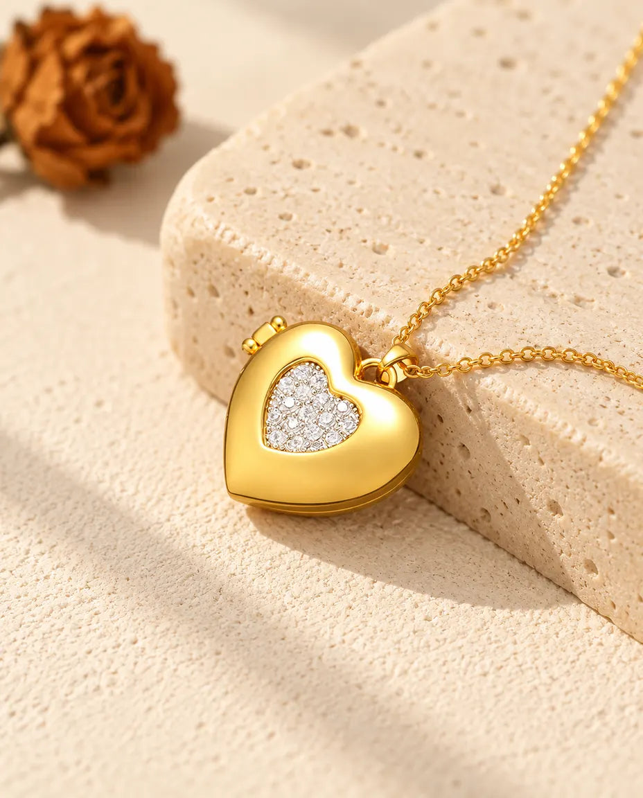 Gold tone two-tone pave heart photo locket necklace resting on a travertine block
