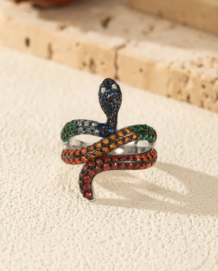Snake Ring in 925 Sterling Silver with Rainbow Coloured Stones - standing upright on a cream textured surface