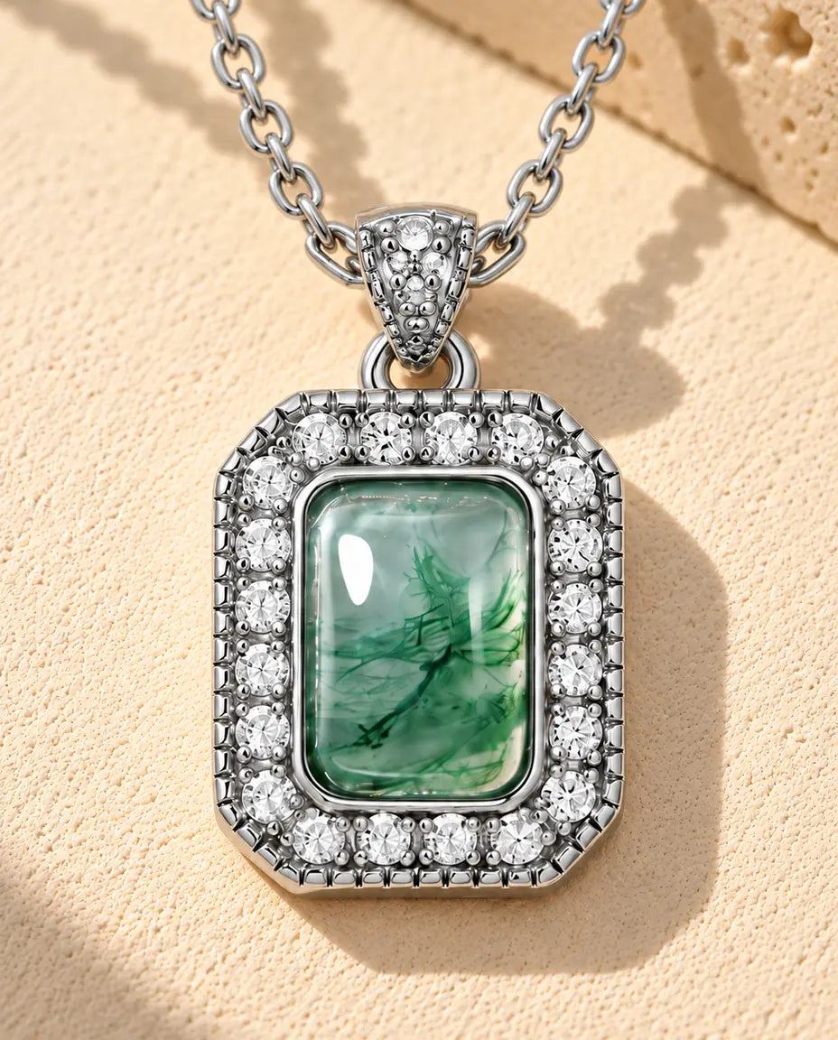 Rectangle Moss Agate Halo Necklace in 925 Sterling Silver - lying on a cream textured surface beside a travertine block