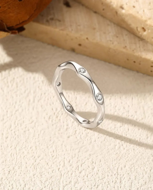 Wavy Moissanite Band Ring in 925 Sterling Silver - standing upright on a cream textured surface